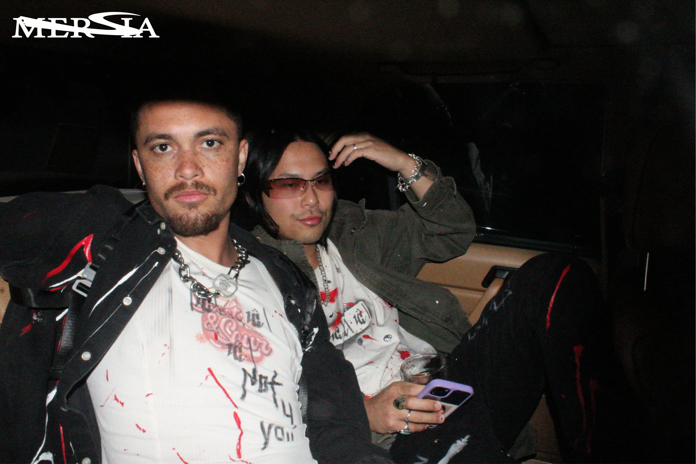 Two models wearing Keygen garments seated in the back of a car.