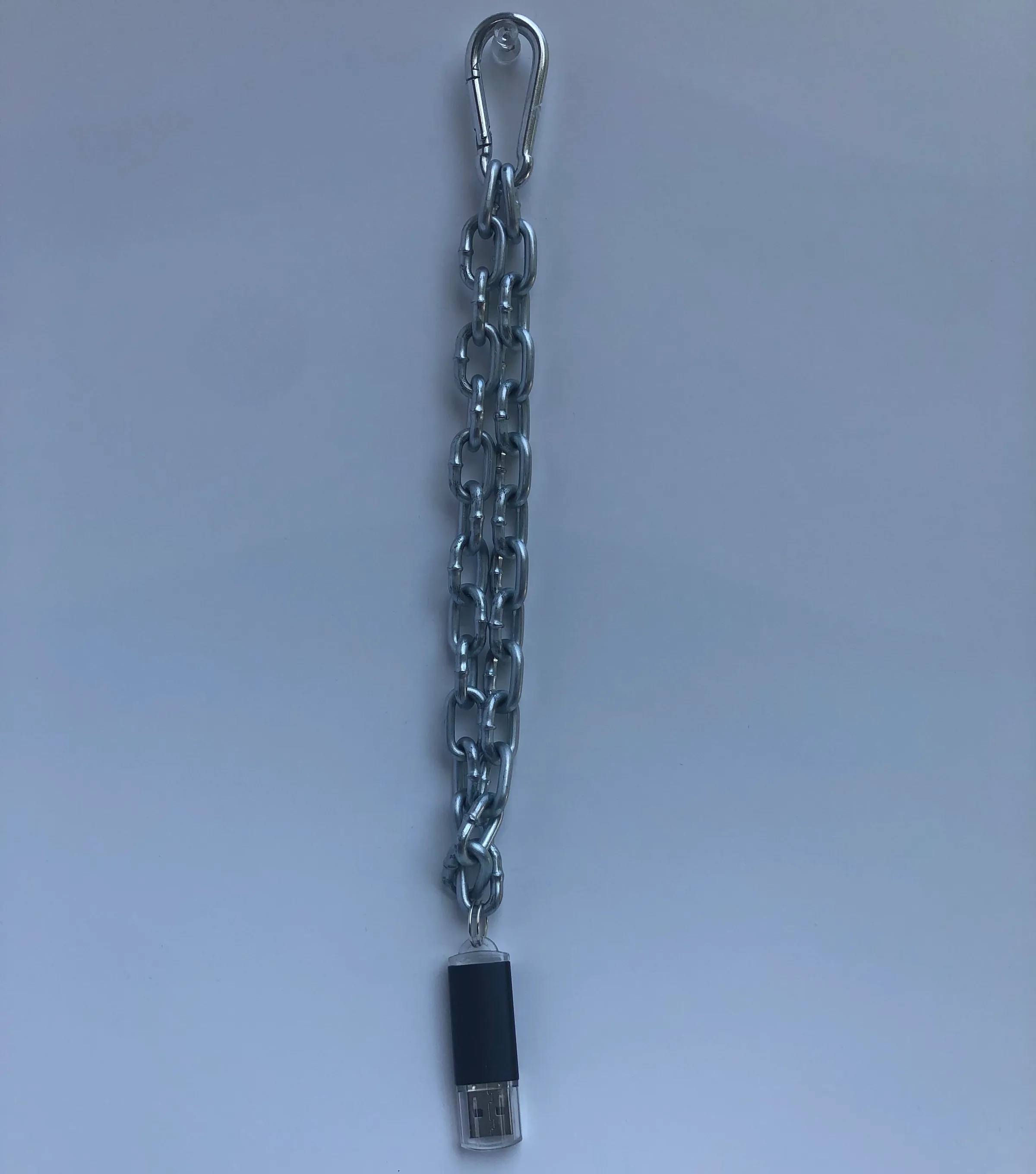 A black USB drive suspended from a hand-built silver chain.