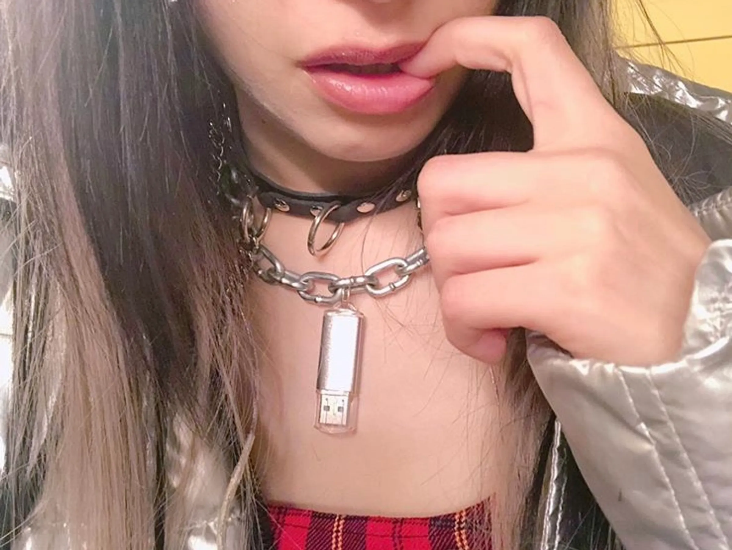 Close view of a silver USB drive worn on a chain.